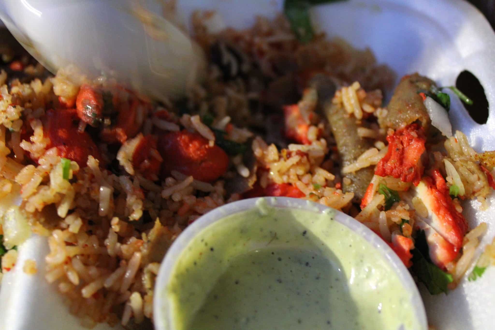 The real biryani as served — red rice with green sauce in takeout container